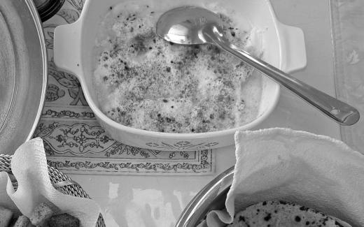 A metal serving spoon in a plate of food, alongside other plates of food.